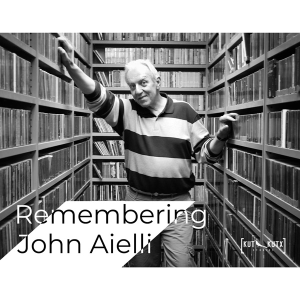 John Aielli standing in a music library lined with CDs.